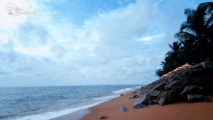 Tranquil tropical beach with soft sand, gentle waves, rocky shoreline, and palm trees shading orange-and-white umbrellas near a resort area. The sky is partly cloudy, evoking a peaceful vacation vibe. Logo in corner reads 'Brio Travels' with palm trees and airplane graphic." Kerala tour packages for family
